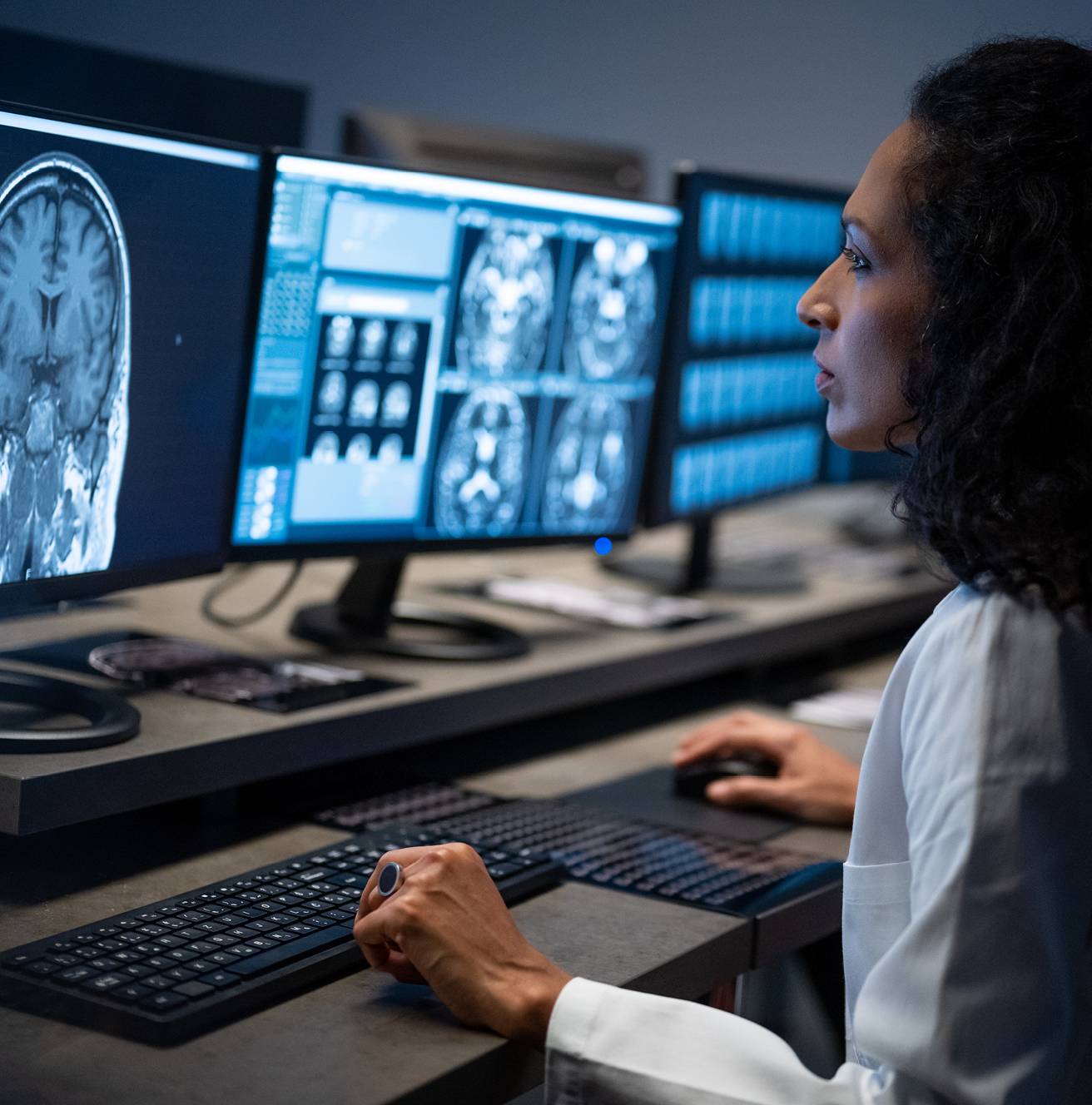 Medical professional reviewing scans on multiple monitors