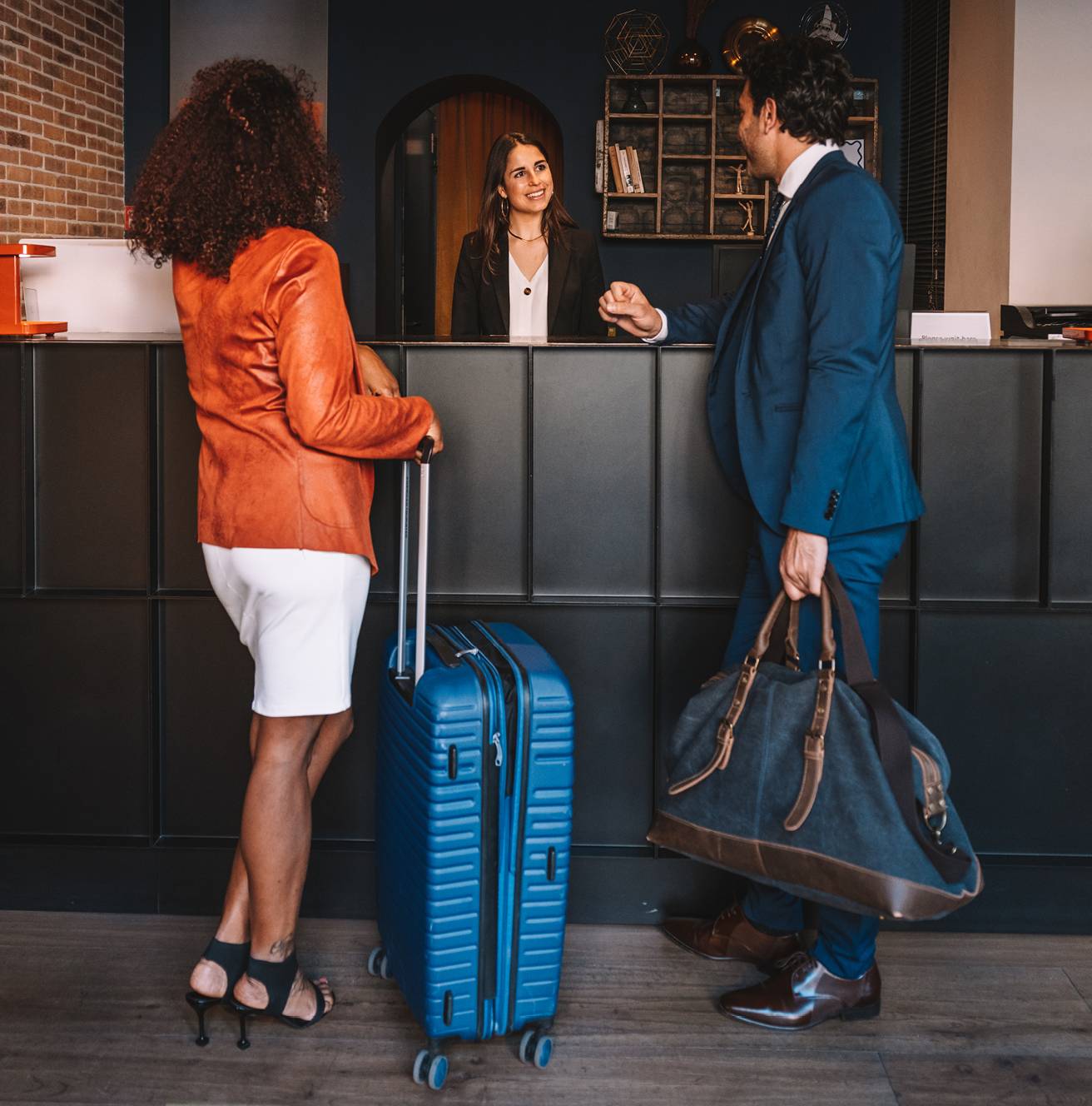 Travelers with luggage checking in at a hotel lobby
