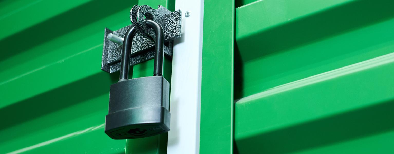 Black padlock securing the door of a green shipping container