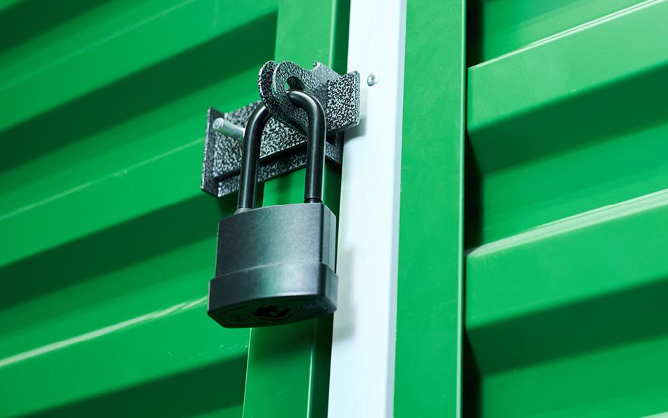 Black padlock securing the door of a green shipping container