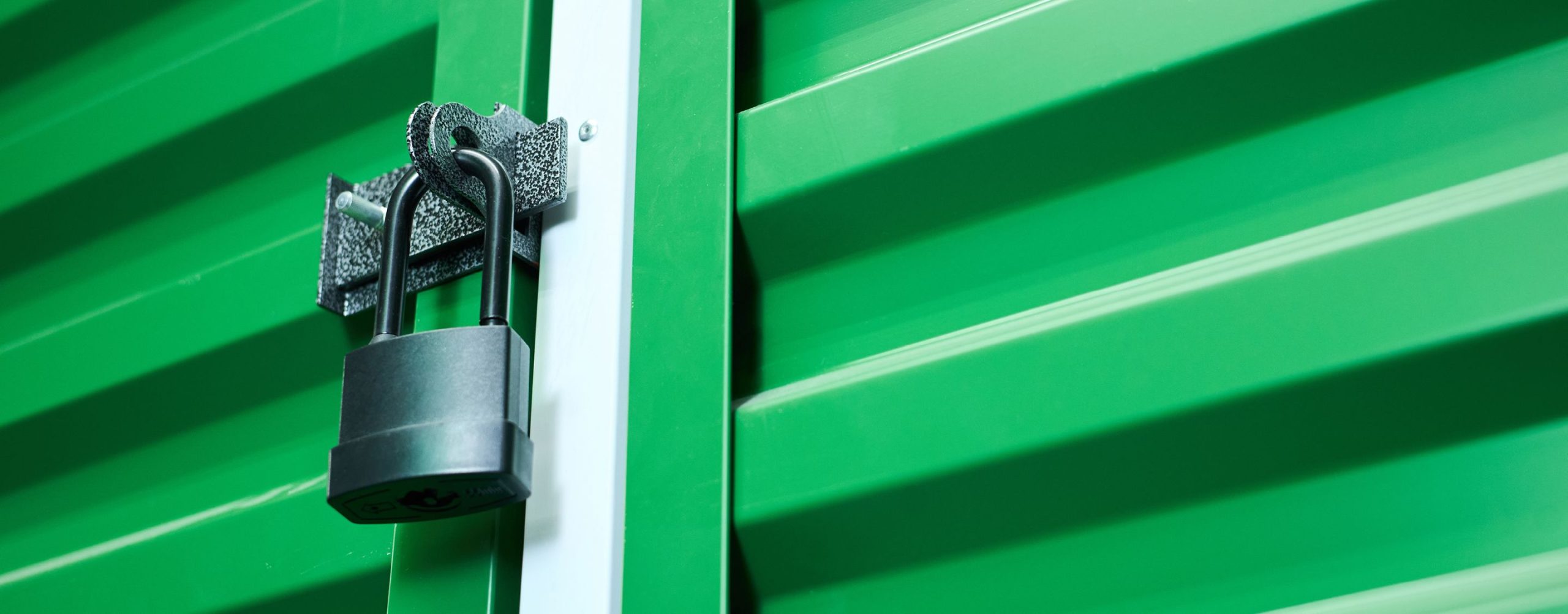 Black padlock securing the door of a green shipping container