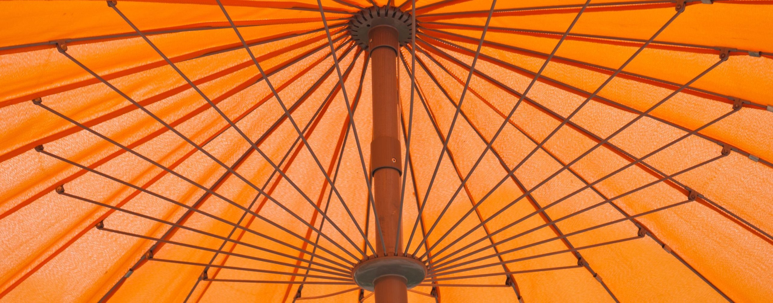 Looking up into the underside of an orange patio umbrella